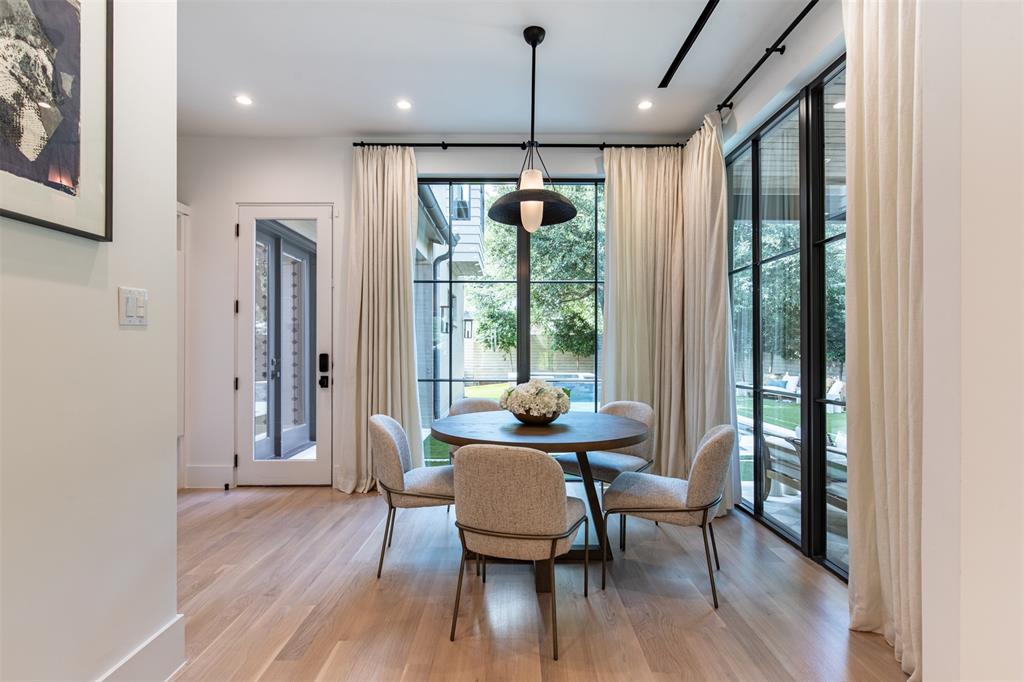 Wood-finish flooring, floor-to-ceiling black-framed windows, and a multi-tiered pendant light fixture