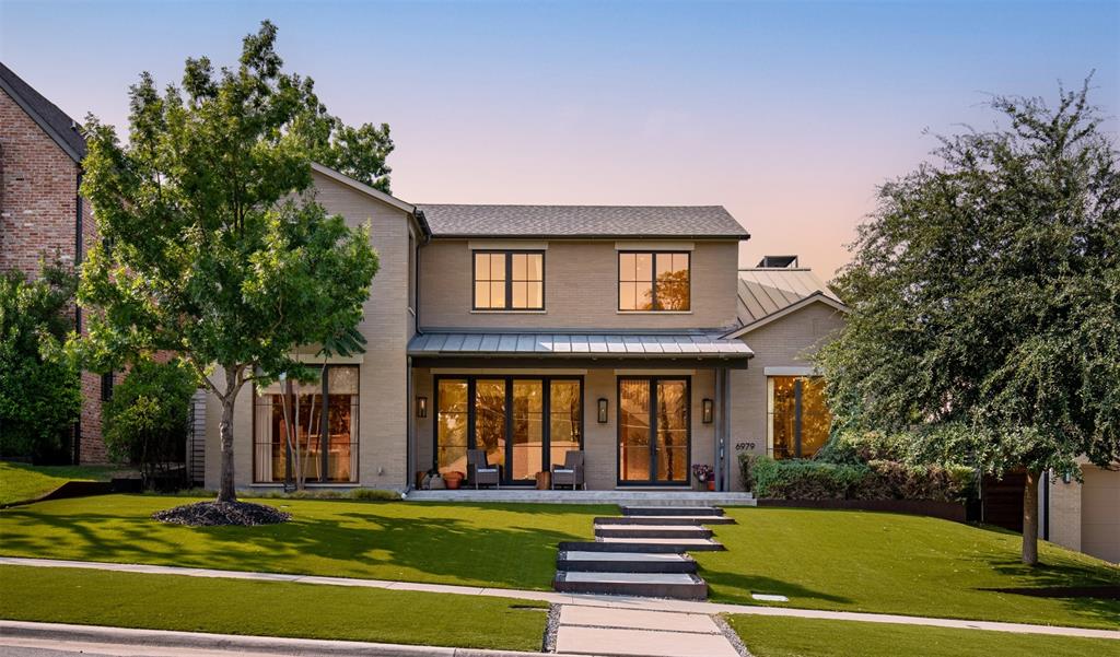 Two-story brick exterior featuring a standing-seam metal roof, black-trimmed windows, a metal-roofed front porch, and tiered concrete walkways