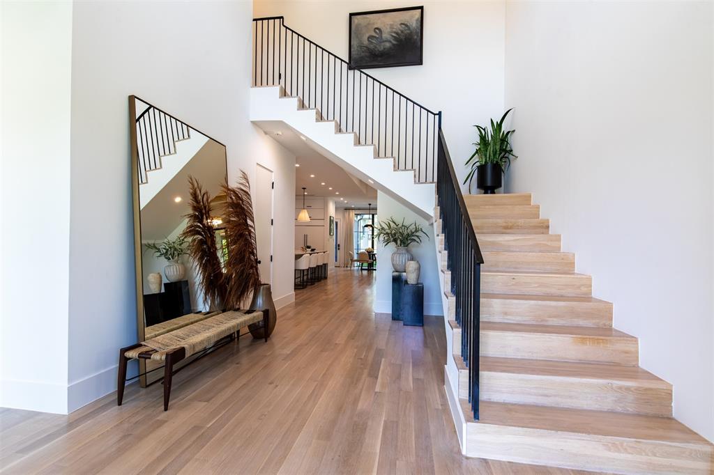 Entryway featuring wood-finish flooring, a staircase with custom light-toned wood treads, and minimalist black metal railings