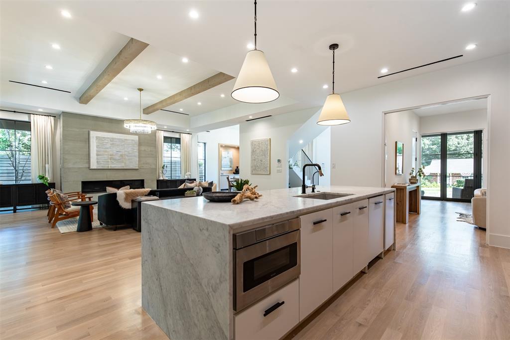 Kitchen island featuring a waterfall stone countertop, integrated microwave, and undermount sink with a matte black faucet