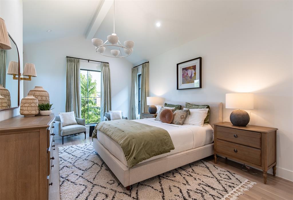 Vaulted ceilings with a prominent beam, wood-finish flooring, and expansive windows featuring dark frames and integrated hardware