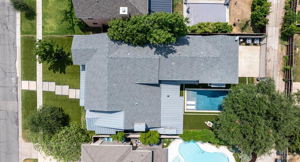 Aerial perspective featuring a multi-gabled roofline, concrete paver walkway, rectangular swimming pool, and manicured turf