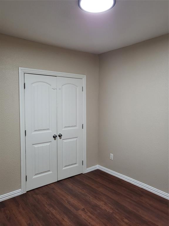 Wood-finish flooring, white arched double-door closet, and neutral wall tones
