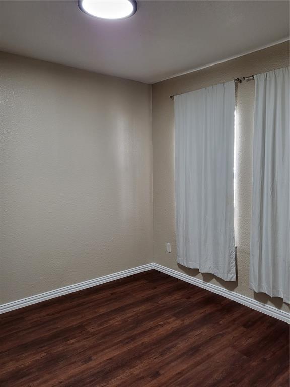 Neutral-toned interior space featuring wood-finish flooring and a flush-mount ceiling light fixture