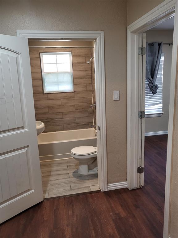 Bathroom featuring wood-finish tile flooring, tub-shower combination with wood-finish tile surround, and wood-finish flooring in the exterior space