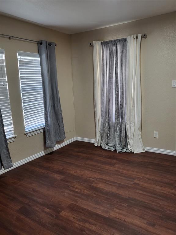 Interior room featuring wood-finish flooring, two multi-pane windows with horizontal blinds, and metal curtain rods