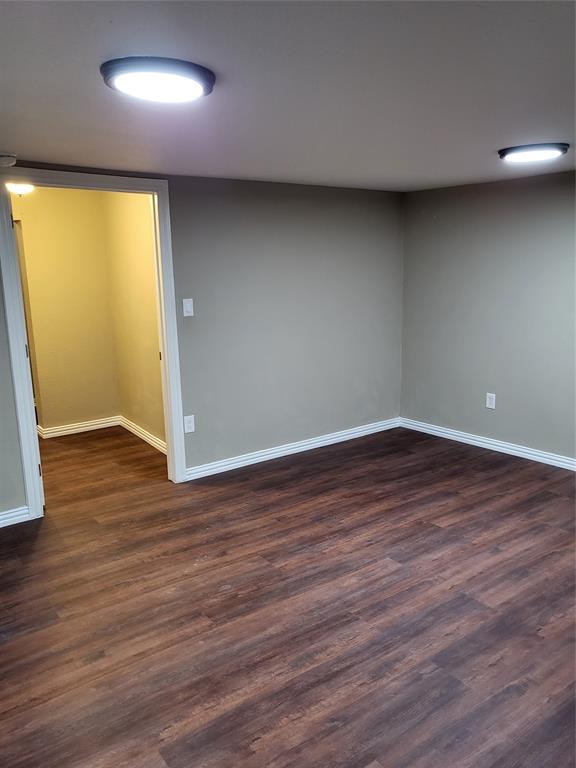 Interior room featuring wood-finish flooring, neutral wall tones, and dual ceiling-mounted light fixtures