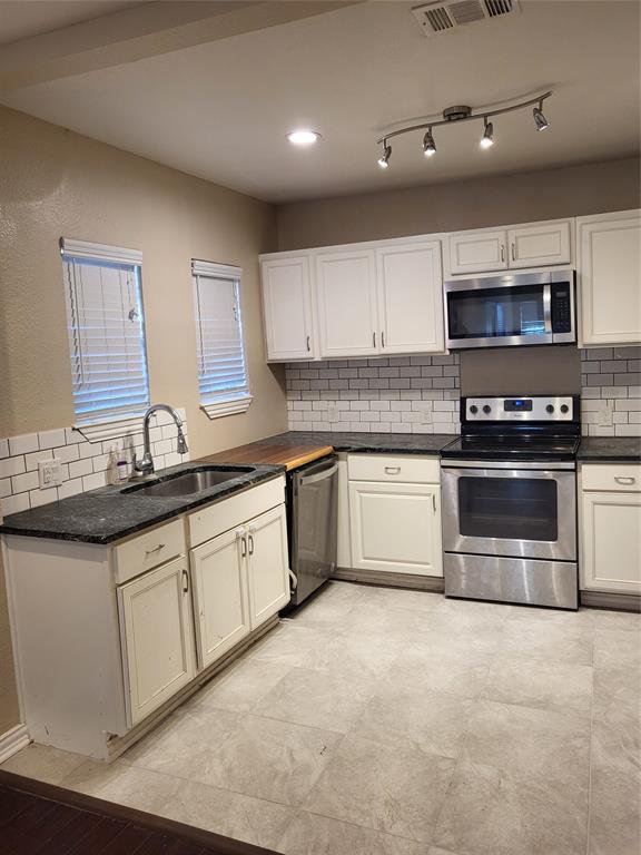 Kitchen featuring white shaker-style cabinetry, stone-finish countertops, subway tile backsplash, stainless steel appliances, and adjustable track lighting