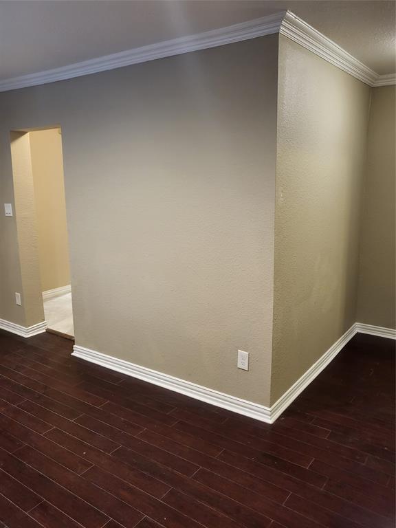 Dark wood-finish flooring complemented by white crown molding and neutral wall paint