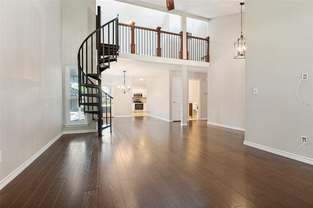 Soaring ceilings with a decorative chandelier, dark wood-finish flooring, and a unique black spiral staircase