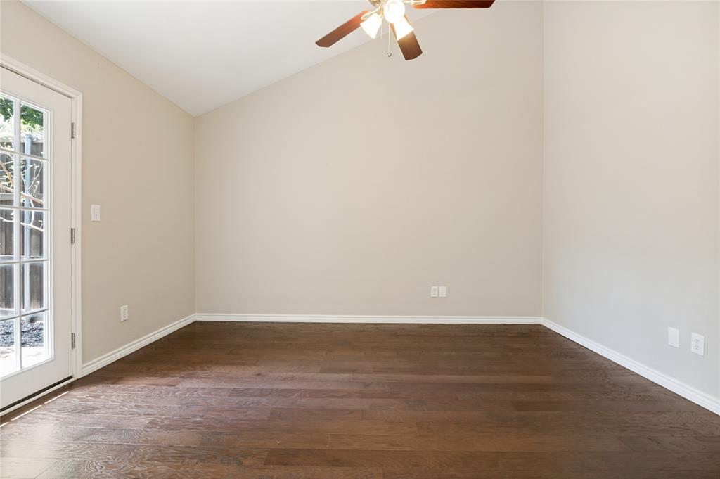 Vaulted ceiling with a ceiling fan, wood-finish flooring, and a glass-paneled door
