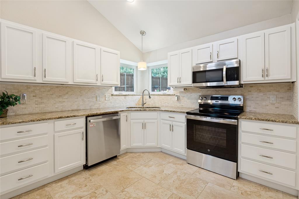 Kitchen featuring white cabinetry, light-toned tile flooring, light-toned patterned countertops, mosaic tile backsplash, and stainless steel appliances