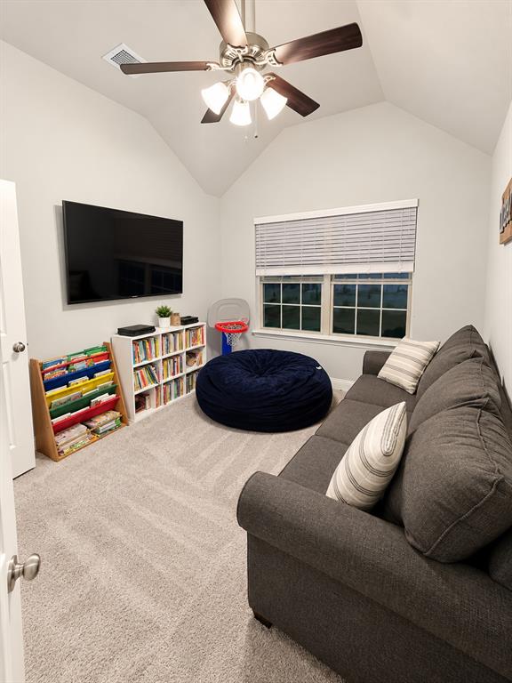 Versatile carpeted room with a ceiling fan and large window, ideal as a media room, game room, or home office.