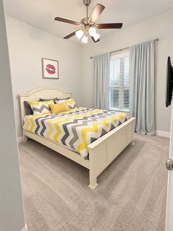 Comfortable bedroom with a ceiling fan and soft natural light.