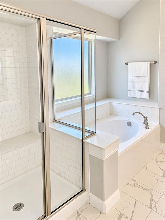 Primary bath features a soaking tub and a separate glass-enclosed shower.