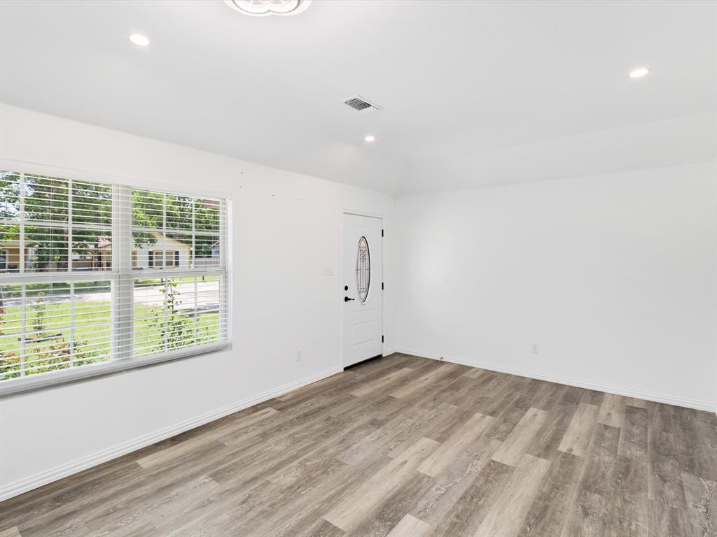 Interior space featuring wood-finish flooring, recessed lighting, white walls, a single-pane window with horizontal blinds, and a white exterior door with an oval glass inset