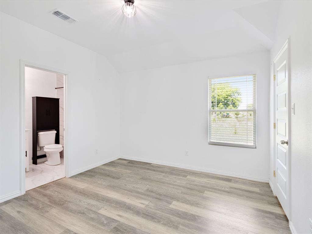 Neutral-toned wood-finish flooring, vaulted ceilings, and a multi-pane window with horizontal blinds