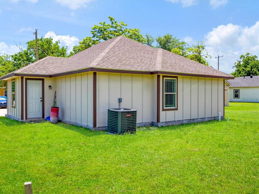 Exterior featuring vertical panel siding, a hipped roof with composition shingles, and an outdoor HVAC unit set upon an expansive lawn