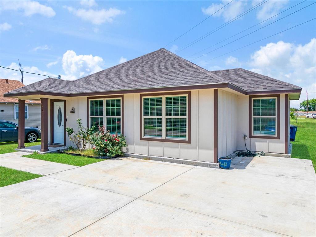 Single-story exterior featuring a hip roof, panel siding with contrast trim, multiple grid-pane windows, and an attached concrete driveway
