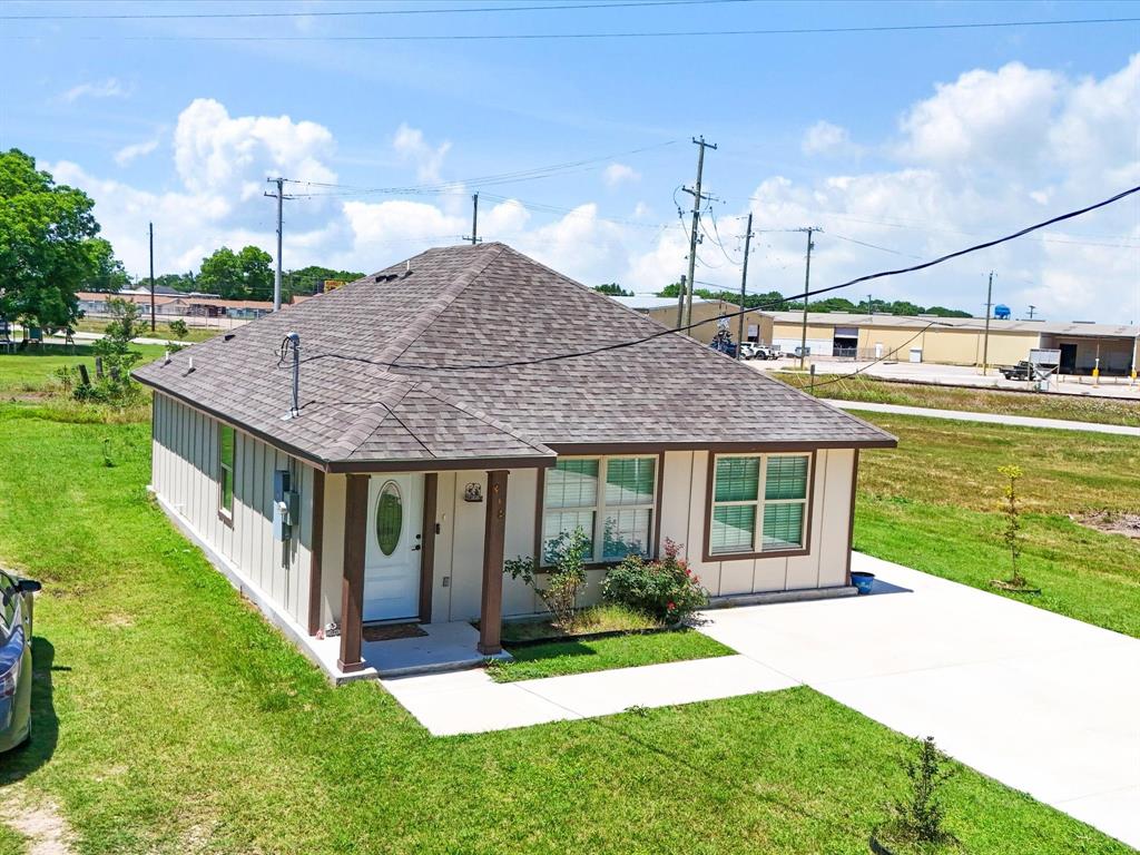Single-story exterior featuring vertical siding, a hipped roof with asphalt shingles, a covered entryway with squared pillars, and a concrete driveway