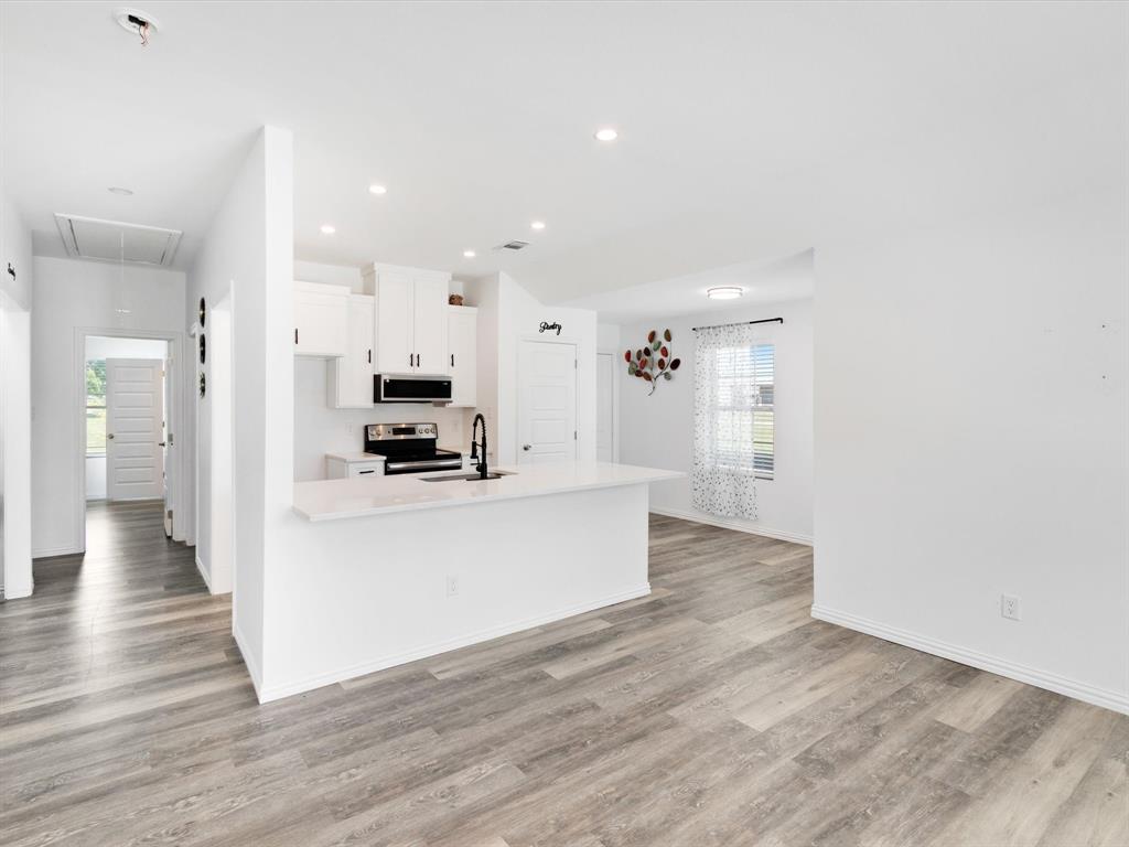 Kitchen featuring white cabinetry, an island with stone-finish countertops, recessed lighting, and wood-finish flooring