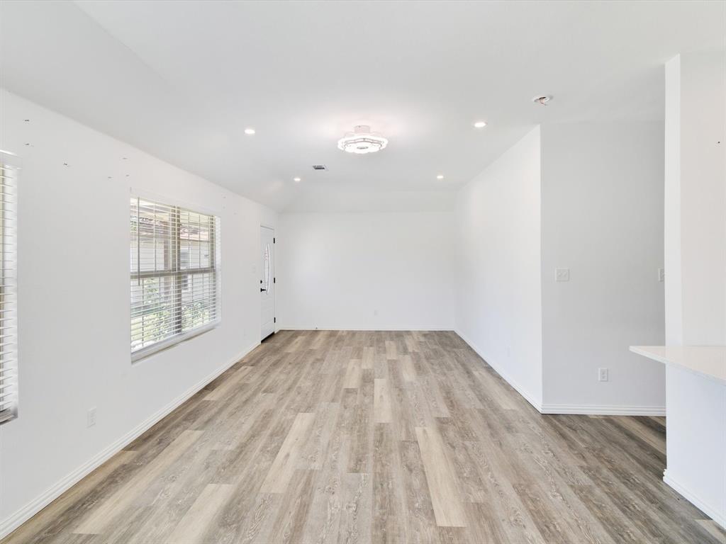 Interior space featuring wood-finish flooring, recessed lighting, a modern ceiling light fixture, and multiple windows