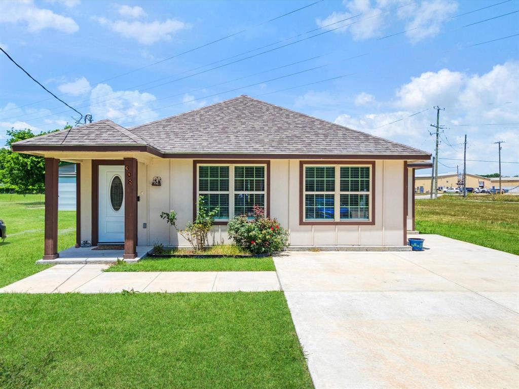 Single-story exterior featuring a hip roof, covered front porch with support pillars, multi-pane windows, and a concrete driveway