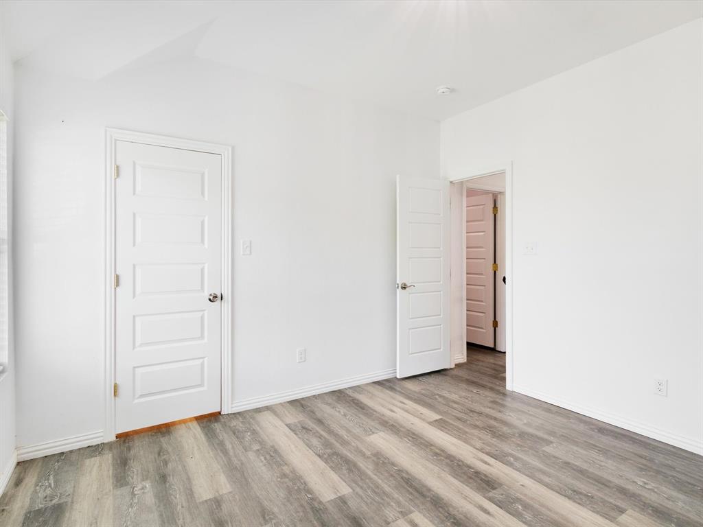 Wood-finish flooring, neutral white walls, and five-panel interior doors with metallic hardware