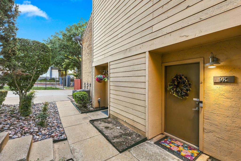 Exterior entrance featuring horizontal wood-finish siding, textured stucco wall cladding, covered porch area, and attached gooseneck wall lighting