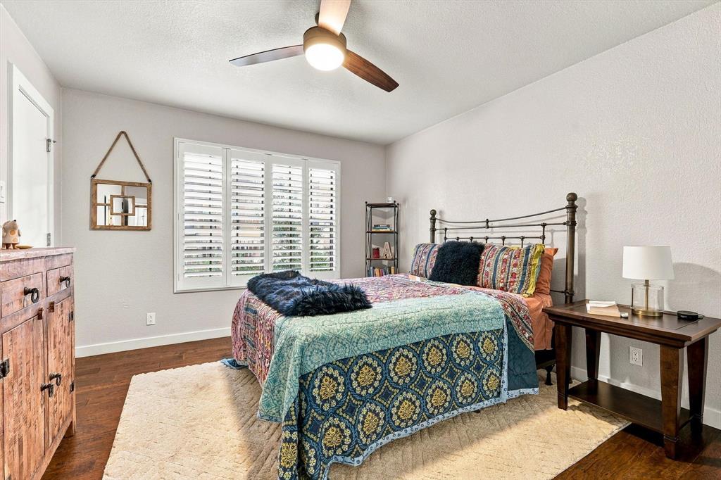 Wood-finish flooring, plantation shutters, and a central ceiling fan with integrated lighting