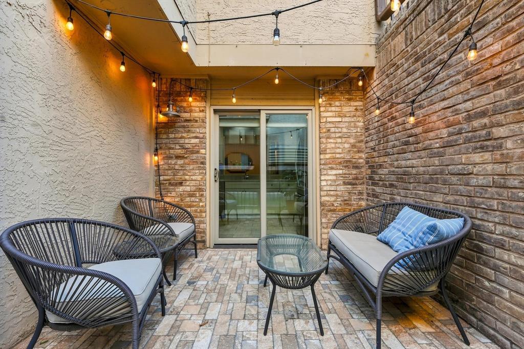 Enclosed courtyard featuring masonry brick walls, textured stucco siding, multi-tone stone paver flooring, and sliding glass entry doors
