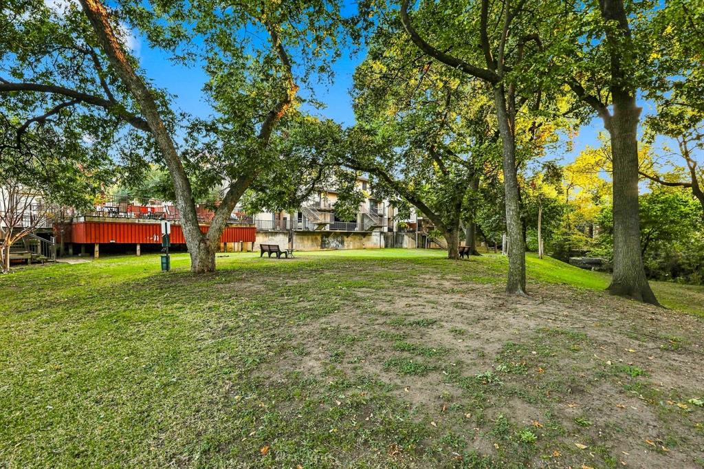 Expansive green space featuring mature trees and a raised wooden deck with railings