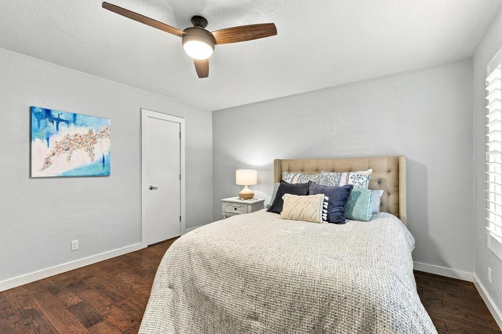 Room featuring wood-finish flooring, a modern three-blade ceiling fan with integrated lighting, and plantation-style window shutters