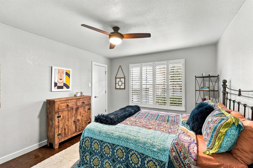 Neutral-toned interior featuring wood-finish flooring, a ceiling fan with integrated lighting, and plantation shutters