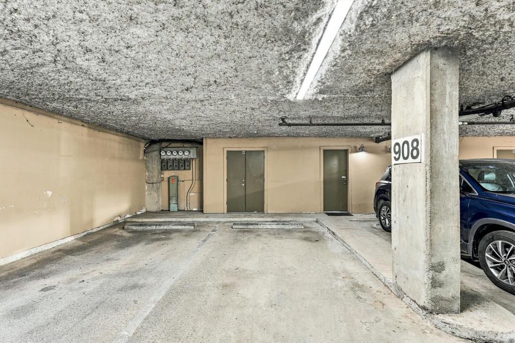 DIRECT ACCESS TO CONDO Covered parking area featuring concrete flooring, structural support columns, ceiling-mounted linear lighting, and direct building access
