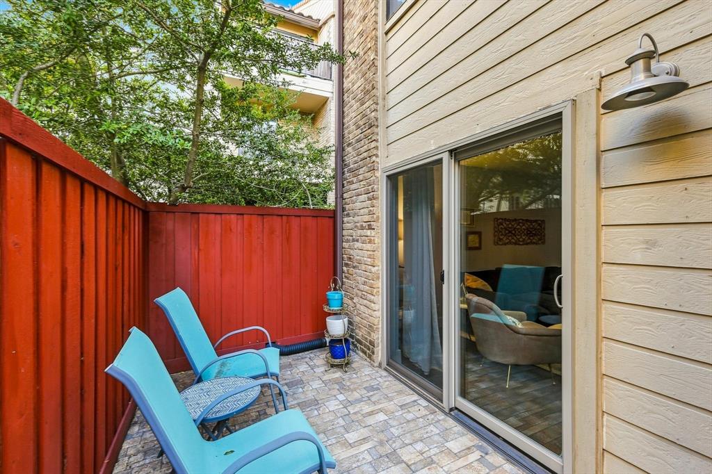 Private patio featuring stone-paver flooring, horizontal lap siding, brick accent wall, and exterior gooseneck lighting