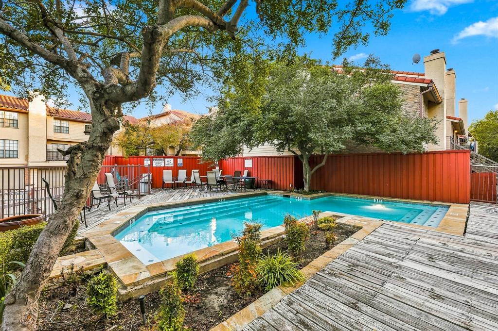 Community swimming pool featuring a tiered stone coping, integrated stepped entry, wood decking, and mature landscaping