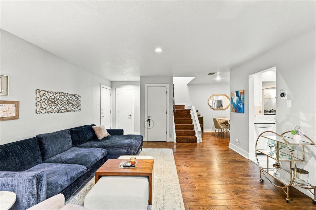 Open-concept interior featuring wood-finish flooring, staircase with carpeted treads, and neutral wall tones