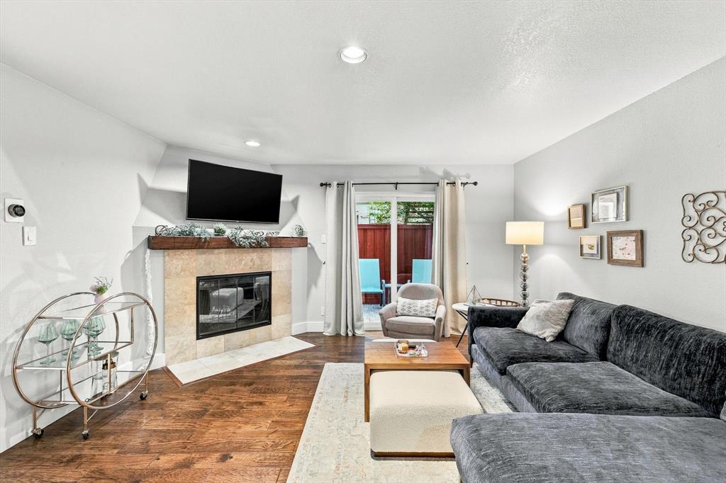 Fireplace featuring a stone tile surround and a wood mantel, wood-finish flooring, and sliding glass doors