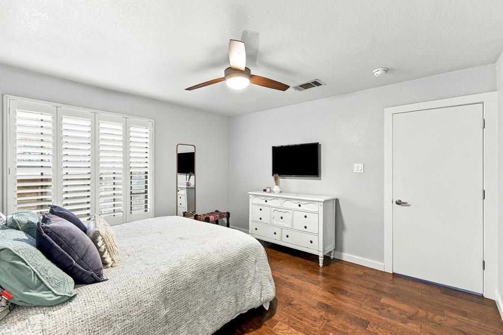 Room featuring wood-finish flooring, plantation shutters, and a central ceiling fan with integrated lighting