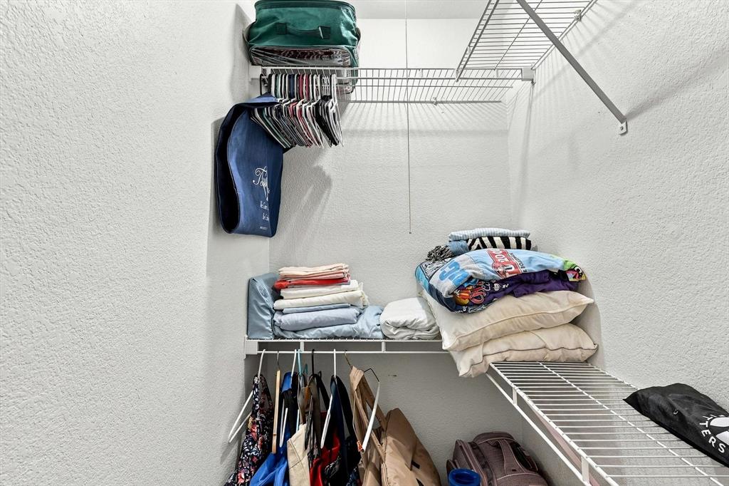 Storage area featuring tiered white wire shelving and a horizontal hanging rod