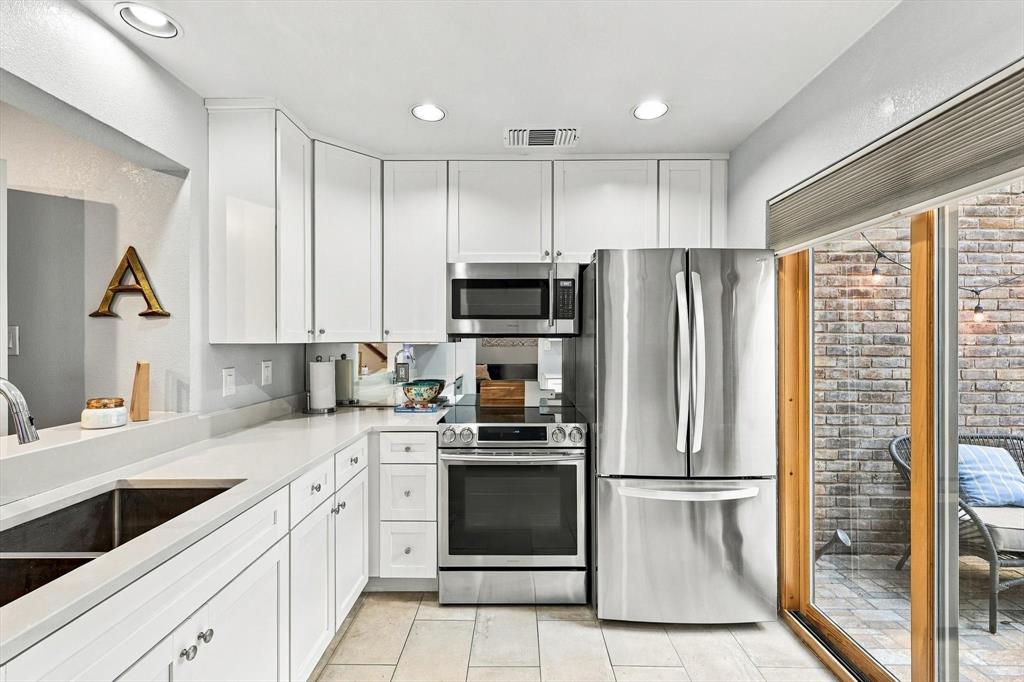 Kitchen featuring white cabinetry, solid-surface countertops, recessed ceiling lighting, stainless steel appliances, and tile flooring