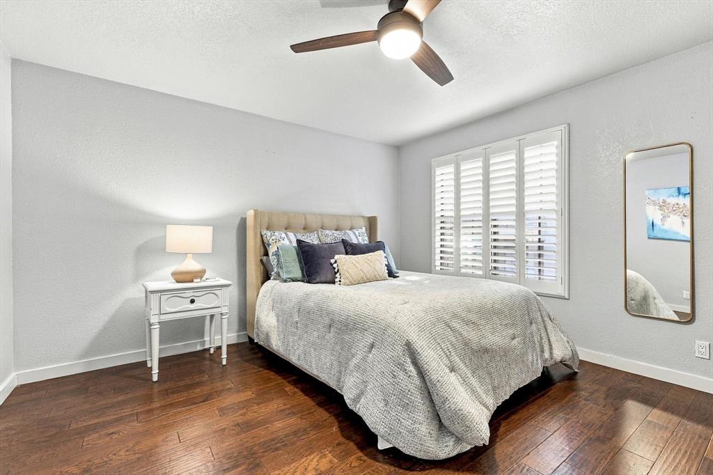 Room featuring wood-finish flooring, plantation shutters, and a central ceiling fan with an integrated light fixture