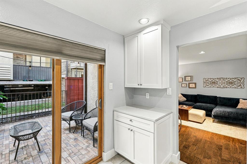 Built-in white cabinetry with stone-surface countertop, sliding glass door, recessed lighting, and paver-stone patio