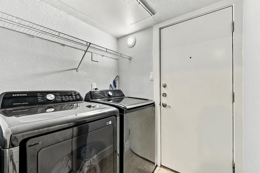 Laundry utility space  access garage featuring a metal wire wall-mounted shelving unit and a solid core door with a security deadbolt