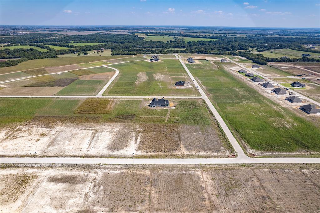 Aerial perspective of expansive residential acreage featuring cleared lots, paved roadways, and surrounding wooded borders