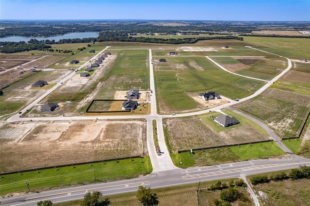 Aerial perspective of residential lots featuring paved roads, concrete infrastructure, and proximity to a water reservoir