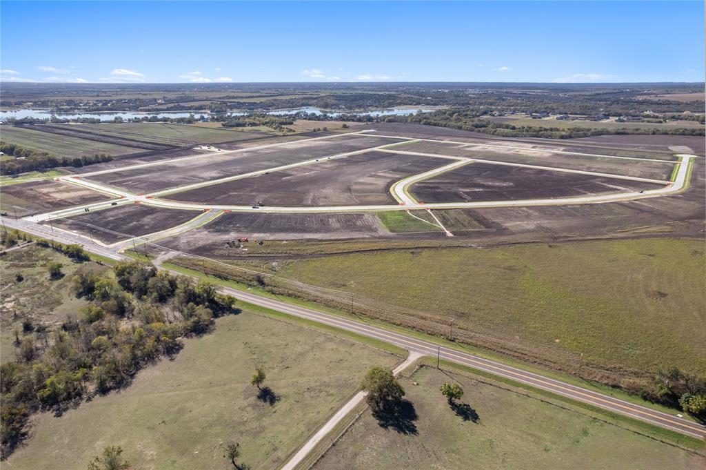 Expansive undeveloped acreage featuring paved roadways, curb infrastructure, and horizon water scenery