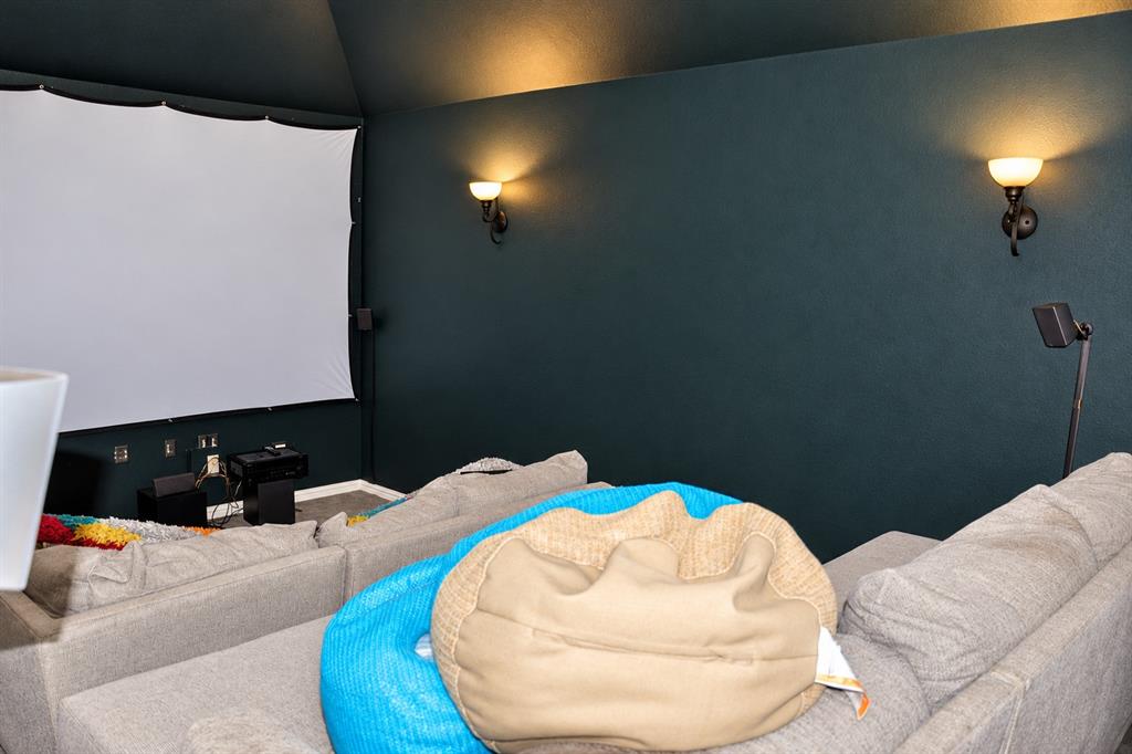 Media room featuring a vaulted ceiling and wall-mounted metal sconces