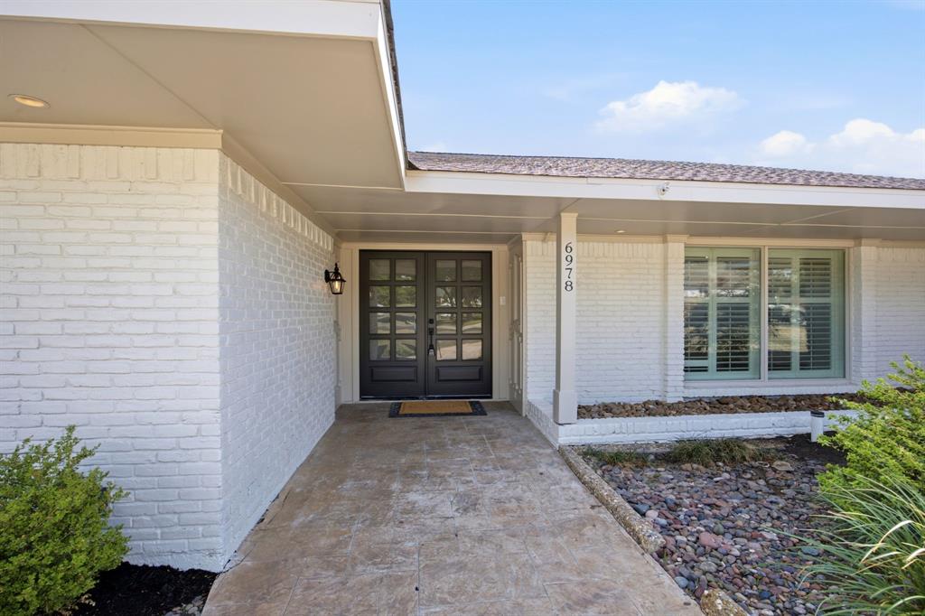 Painted brick exterior featuring a covered porch, stone-finish walkway, double-entry doors with multi-pane glass, and window shutters